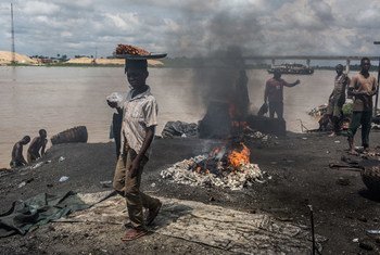On 24 October 2016 in Yenagoa, Bayelsa State, Nigeria, children pass in front of a flame fed by waste and rubber materials in order to make Kanda, a type of smoked meat, at an abattoir.