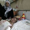 Familiar cuida de menino de três anos no Hospital Al-Shifa, ferido numa explosão que matou 12 membros da sua família. 