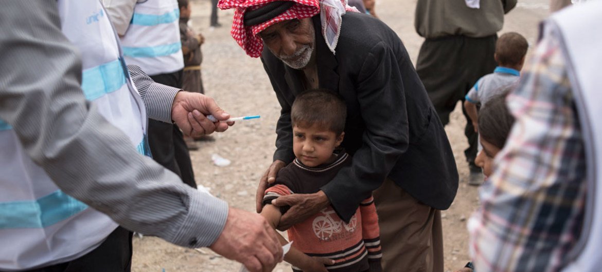 صبي من الذين فروا من قرية جنوبي الموصل، العراق، يتلقى التطعيم ضد الحصبة من فريق الحكومة المحلية  الذي تدعمه اليونيسف. المصدر: اليونيسيف / ليندساي ماكنزي