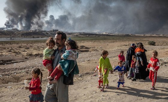 A family displaced by fighting in the village of Shora, 25 kilometres south of Mosul, Iraq, walk towards an army checkpoint on the outskirts of Qayyarah. Photo: UNHCR/Ivor Prickett