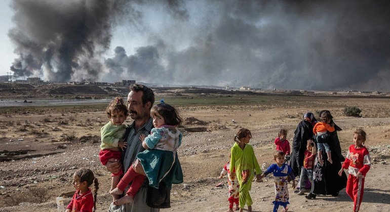 A family displaced by fighting in the village of Shora, 25 kilometres south of Mosul, Iraq, walk towards an army checkpoint on the outskirts of Qayyarah. Photo: UNHCR/Ivor Prickett