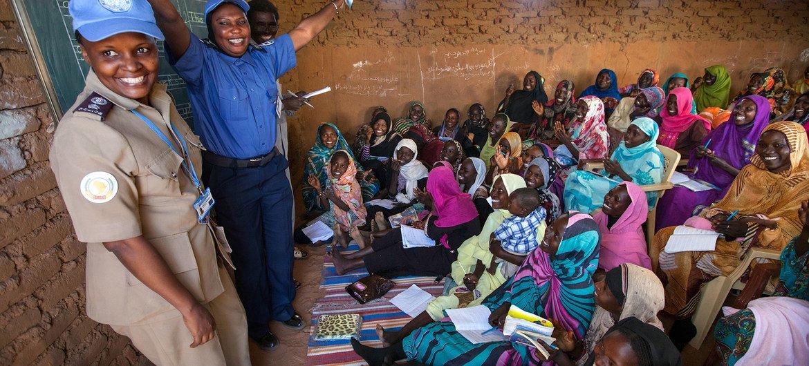 UN police officers Mwamini Rwantale (Tanzania) and Nyima Barrow (Gambia) interacting with women who receive English classes in the Abu Shouk camp for internally displaced persons in North Darfur. 