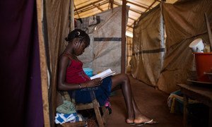 A 14 year-old girl reads a book beneath a makeshift shelter at the Grand Séminaire Saint Marc de Bimbo site for internally displaced people, in Bangui, Central African Republic.