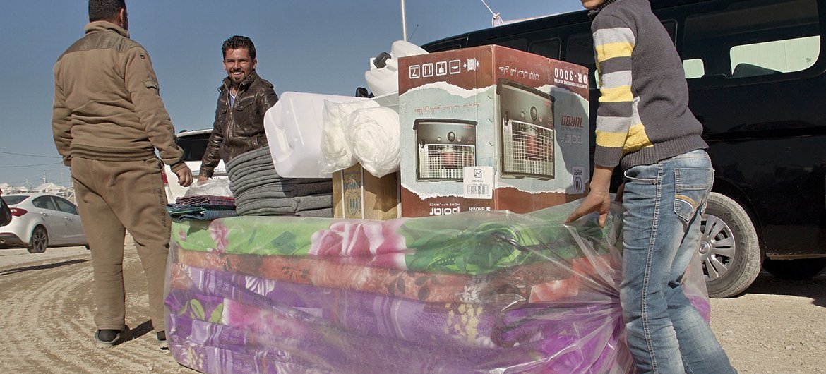 Internally displaced Iraqis push their emergency aid relief package, containing mattresses, blankets, a stove and other essentials to their tents at Qaymawa camp.