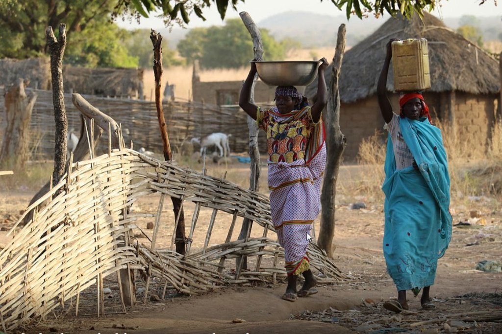 Women in Gordil, Central African Republic (CAR), carry food and water back home as evening descends.