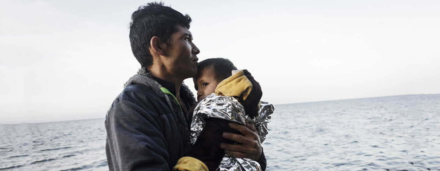 一位阿富汗难民和孩子从土耳其乘坐皮划艇经爱琴海抵达了希腊的一个小岛。