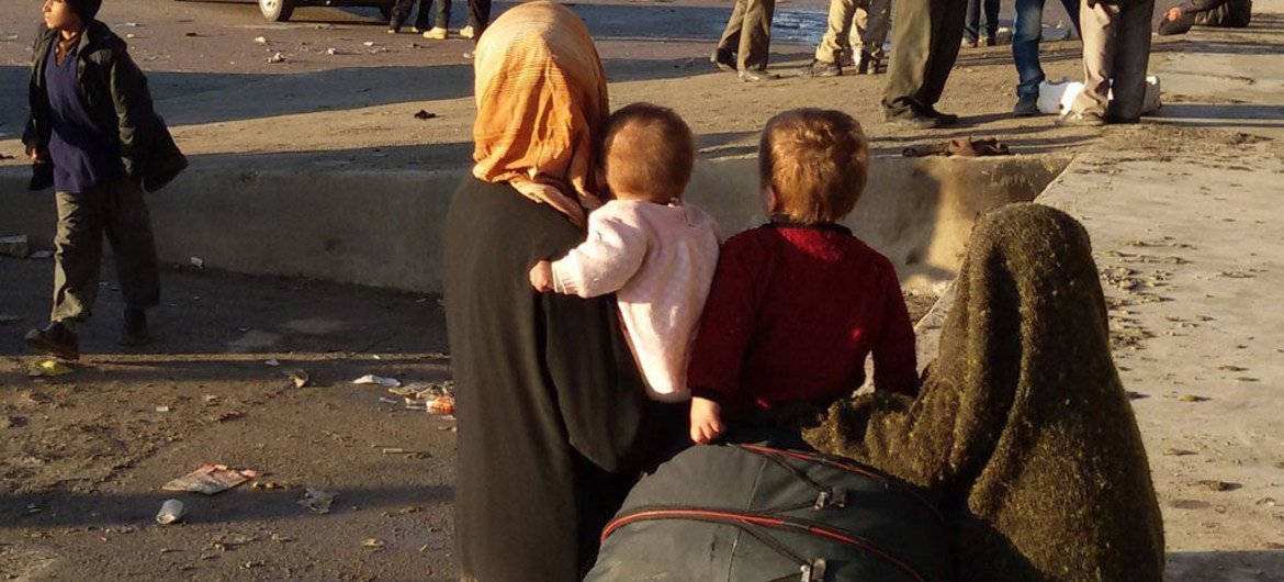 A woman and her children wait for transportation in Aleppo, Syria.