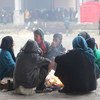 أطفال يجلسون مع أسرهم حول النار للتدفئة في ساحة مستودع كبير في جبرين، يستخدم الآن كمأوى لآلاف الأسر الذين فروا من أعمال العنف في شرق حلب. المصدر: اليونيسف / UN043357 / العيسى