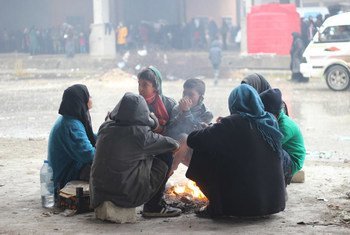 Children and their parents gather around a fire to keep warm in the yard of a large warehouse in Jibreen, now used as a shelter for thousands of families who fled violence in eastern Aleppo.