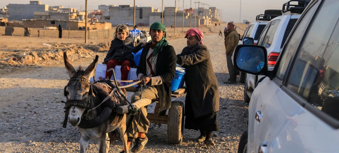 Une famille transporte des fournitures humanitaires sur un chariot dirigé par un âne depuis un centre de distribution situé dans la partie est de Mossoul, en Iraq.