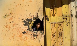 A young girl looks through a hole in the wall from damage from conflict in a school in Ramadi, Anbar Governorate, Iraq. Photo: UNICEF/Wathiq Khuzaie