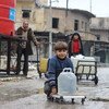 В Восточном Алеппо, Сирия, мальчишки  и мужчины  получают банки с водой  в рамках проекта, поддерживаемого ЮНИСЕФ. Фото ЮНИСЕФ/ Кудер Аль-Исса