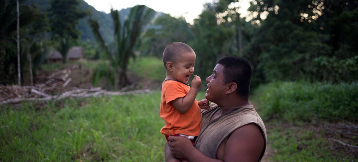 In Belize, two-year-old Abner laughs while being carried by his father, James Choc.