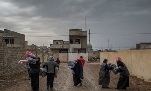 Recipients of UNHCR blankets walk back to their home after an aid distribution in a liberated area of east Mosul, Iraq.