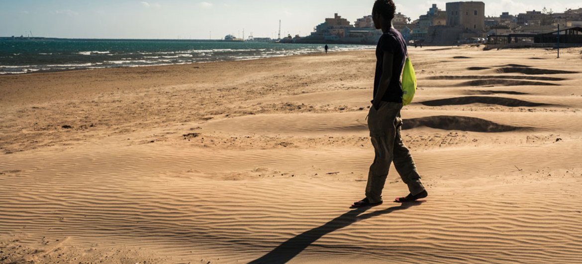 A youngster walks onto the beach during outing from a reception centre that doubles as a lodging station for unaccompanied minors in Pozzallo, Sicily.