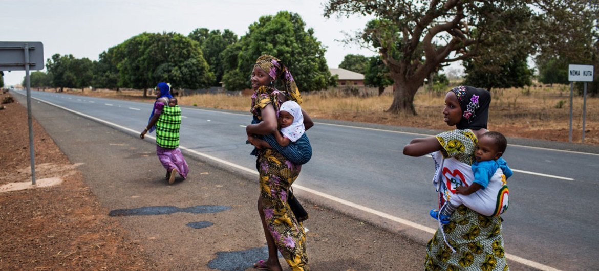 Des femmes rentrent chez elles après avoir fait vacciner leurs enfants sur le site de proximité du centre de santé de Kwinella dans le village de Mandina, en Gambie.