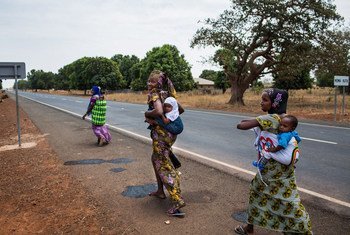 Des femmes rentrent chez elles après avoir fait vacciner leurs enfants sur le site de proximité d'un centre de santé en Gambie.