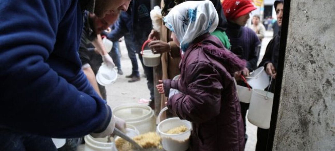 叙利亚阿勒颇的儿童正在从世界粮食计划署工作人员那里领取热餐食。粮食署图片