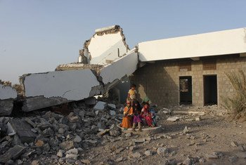 Children sitting in front of a school that was badly damaged in the conflict in Yemen.
