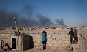 Children look over the wall on the roof of their house at clouds of smoke from oil wells which were set on fire by ISIL when they fled Qayyarah, a town south of Mosul. (file)