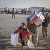 An Iraqi family who fled fighting in Mosul collect aid items at Hasansham camp.