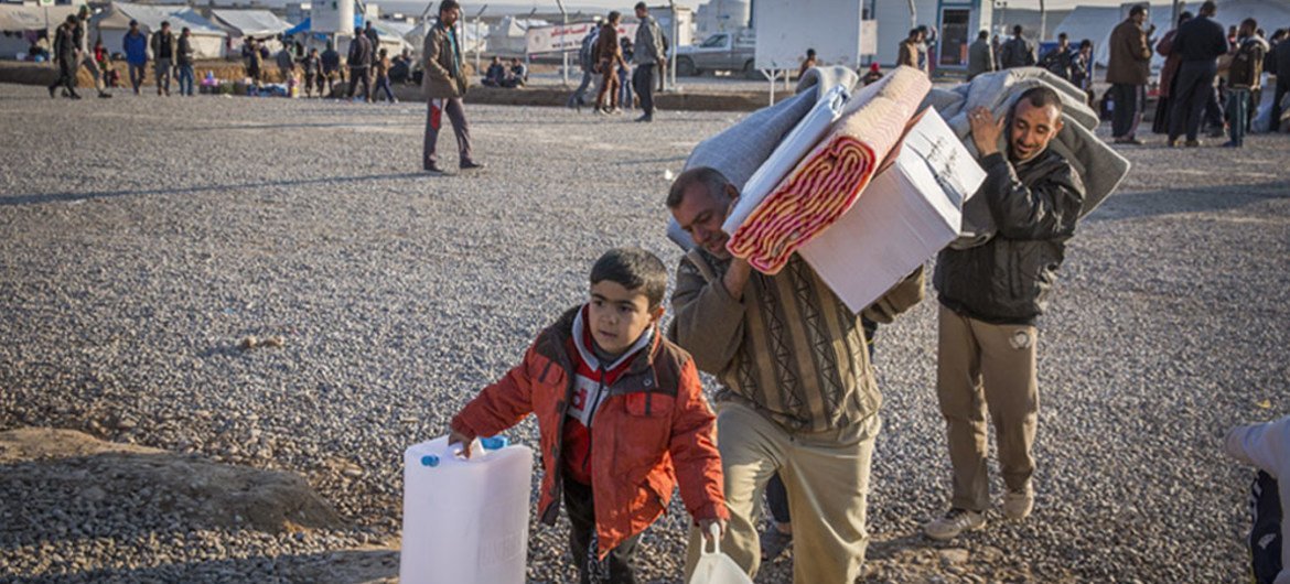 Une famille irakienne qui a fui les combats à Mossoul recueille des articles d'aide au camp de Hasansham.