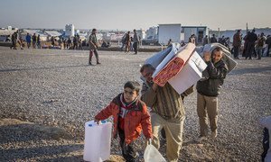 Une famille irakienne qui a fui les combats à Mossoul recueille des articles d'aide au camp de Hasansham.