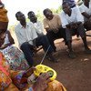 Des résidents du site pour déplacés de Sangari, en République centrafricaine, écoute une radio communautaire qui encourage la tolérance entre les communautés. Photo OCHA/Gemma Cortes