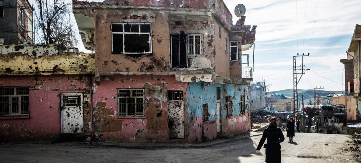 Des habitants de Silvan, une ville dans la province de Diyarbakir, dans le sud-est de la Turquie, passent devant des maisons criblées de balles.