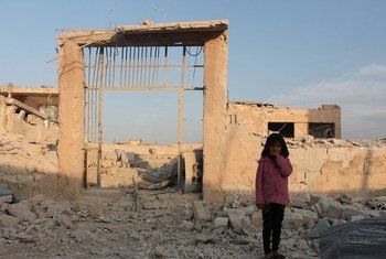 Una niña Siria posa en frente de su escuela destruida por la guerra en Idlib. 