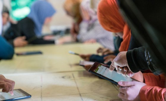 Adolescent girls use cellphones and tablets in a solar kiosk providing internet connectivity in the Za’atari camp for Syrian refugees. 