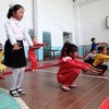 Children doing physical exercises in a school gym in Uzbekistan, among them a child affected by down syndrome.