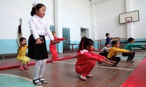 Children doing physical exercises in a school gym in Uzbekistan, among them a child affected by down syndrome.