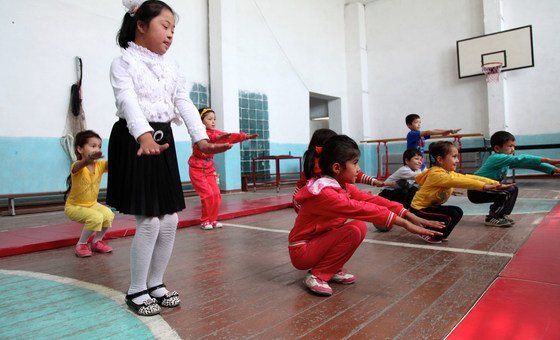 Children doing physical exercises in a school gym in Uzbekistan, among them a child affected by down syndrome.