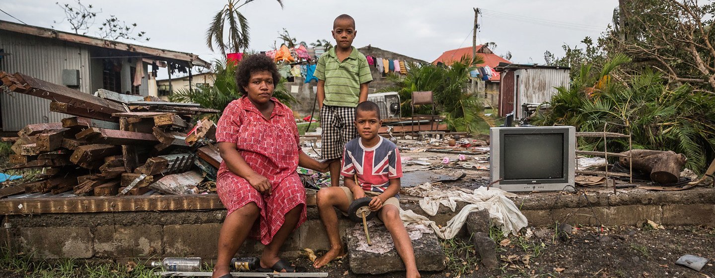 Mereani and her children sitting on brick wall of what used to be their home in Fiji. Their house was just a few metres from the shoreline and suffered extensive damage during strong storm surges at the height of Cyclone Winston. 