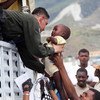 A UN peacekeeper helps a child aboard a truck during the relocation of residents of a camp for displaced persons.