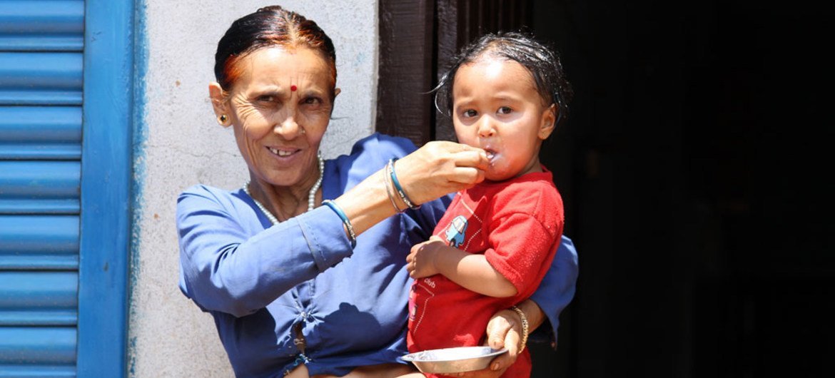 Une grand-mère nourrit sa petite-fille de deux ans à Naubise, Dhading, au Népal.