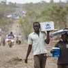 Des réfugiés sud-soudanais avec des articles de secours dans le site pour réfugiés de Bidibidi, en Ouganda. 