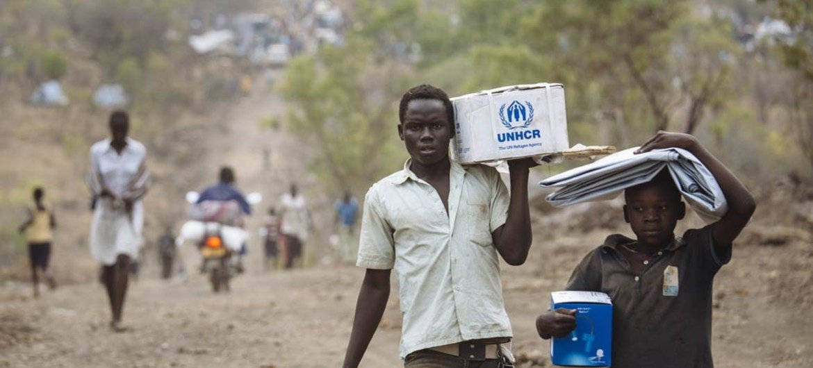 South Sudanese refugees carrying Core Relief Items walk down a road in Bidibidi refugee settlement, Yumbe District, Northern Region, Uganda.  Photo: UNHCR/David Azia