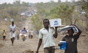 South Sudanese refugees carrying Core Relief Items walk down a road in Bidibidi refugee settlement, Yumbe District, Northern Region, Uganda.  Photo: UNHCR/David Azia