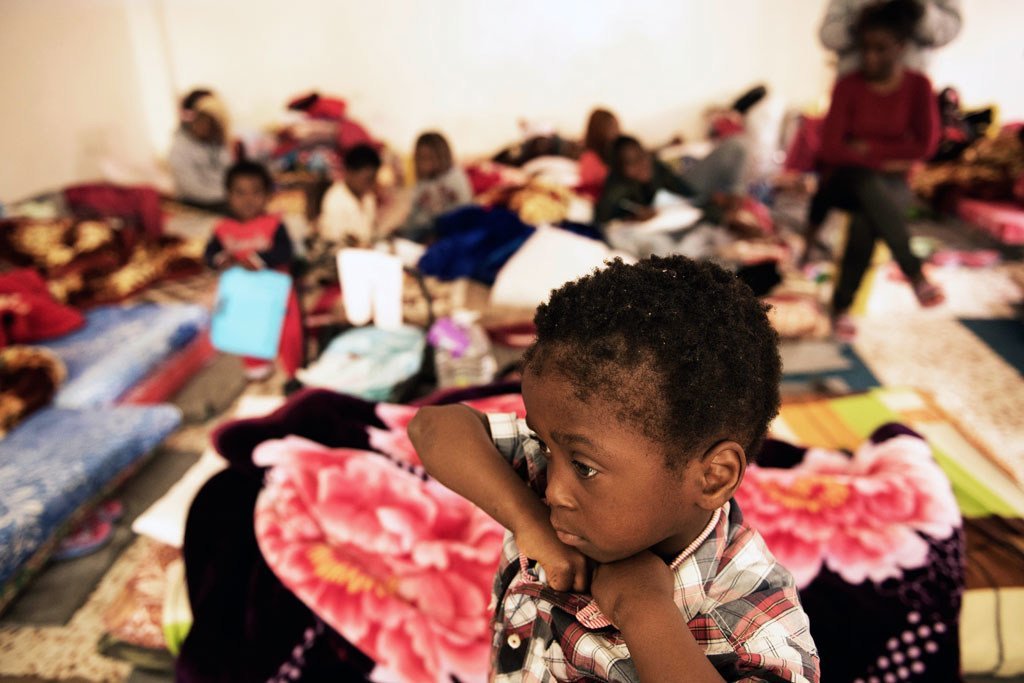 Un enfant dans une pièce où les femmes et les enfants dorment sur de vieux matelas posés sur le sol dans un centre de détention en Libye.