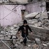 2017年3月11日,一名儿童走在因摩苏尔西部收复战而被空袭摧毁的建筑物的废墟上。