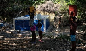 Les résidents remplissent leur récipient sur un site de collecte et de distribution d'eau dans une ville située à une heure de route de Port-au-Prince, en Haïti. 