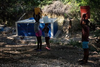 Les résidents remplissent leur récipient sur un site de collecte et de distribution d'eau dans une ville située à une heure de route de Port-au-Prince, en Haïti. 