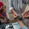 在柬埔寨金边的一个贫困社区，一名卫生工作者正在流动免疫站准备给一名儿童接种疫苗。儿基会图片/Llaurado