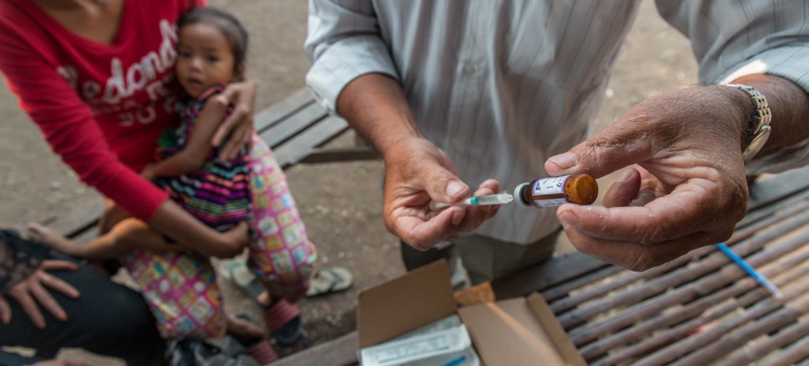 A health worker prepares to administer a vaccine to a child at a mobile vaccination unit, in Svay Pak village, an urban poor community in Rossey Keo district, Phnom Penh, Cambodia.