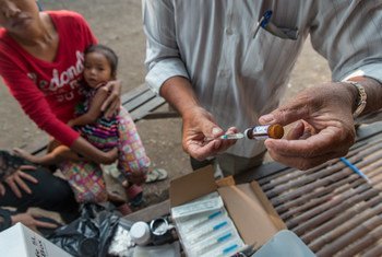 在柬埔寨金边的一个贫困社区，一名卫生工作者正在流动免疫站准备给一名儿童接种疫苗。儿基会图片/Llaurado