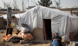 Une femme âgée à l'extérieur de son habitat improvisé en Afghanistan.