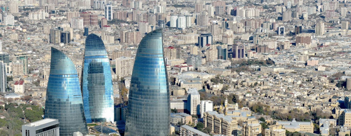 Vue aérienne des Flame Towers à Bakou, en Azerbaïdjan, avec un paysage urbain étendu à l'arrière-plan.