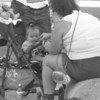 Others standing nearby, a baby sitting in a stroller is fed by her mother at Disney World amusement park in the southern city of Orlando, Florida, in mid-1997. Obesity is a significant nutrition-related problem in the United States.
